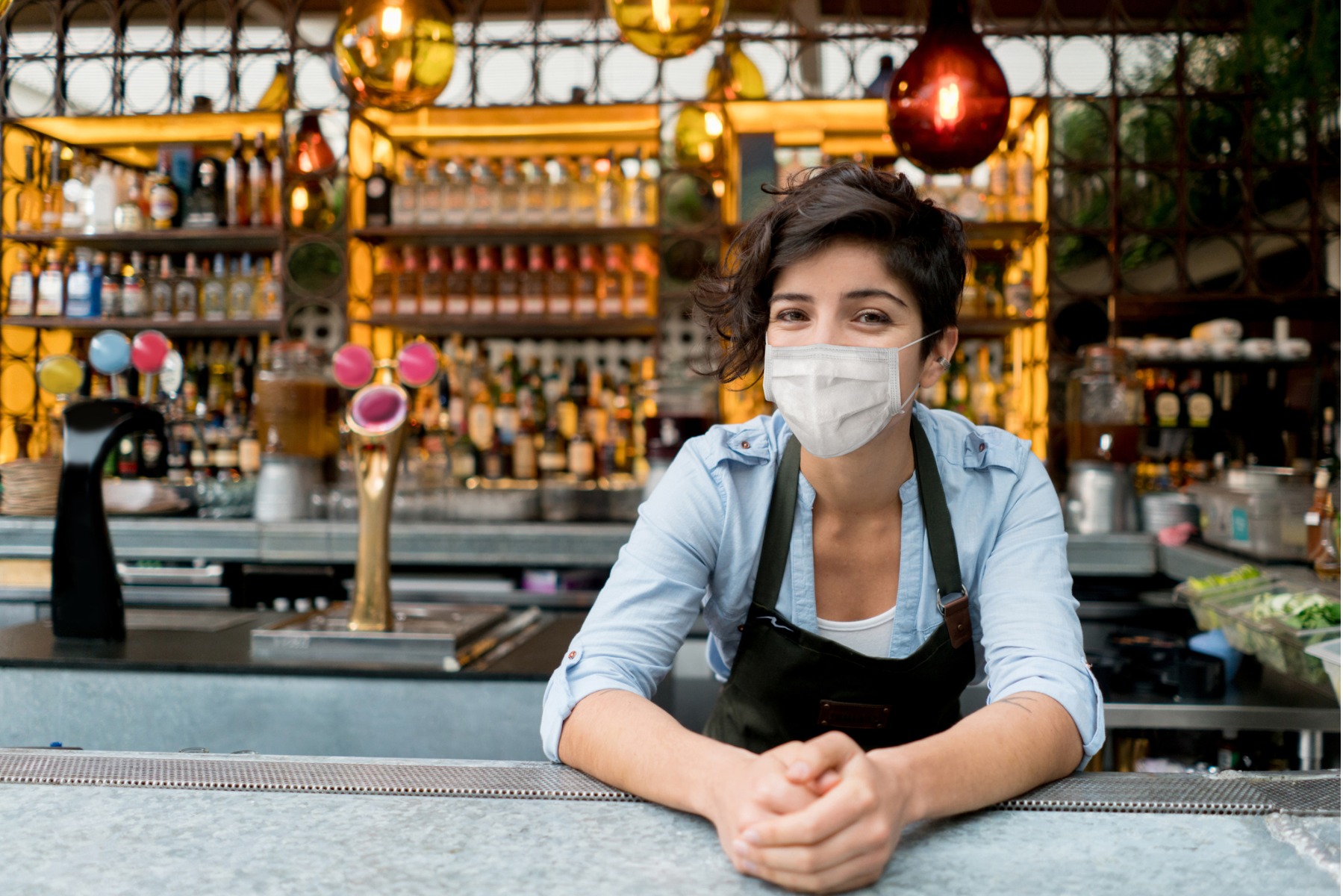 Waitress leaning over the bar with a mask on